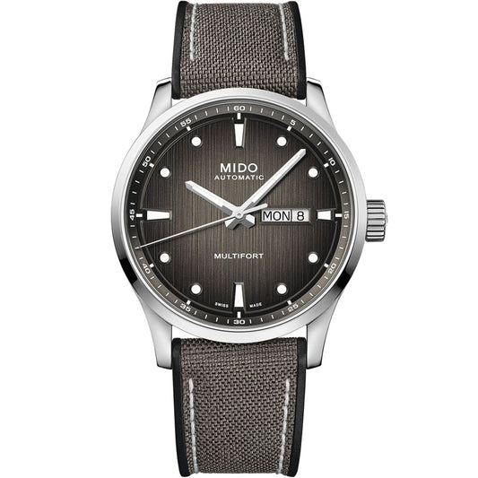 The MIDO Multifort M Automatic 42mm Watch features a textured gray dial, silver hour markers, day-date display at 3 o'clock, and a gray fabric strap with white stitching. Powered by the reliable Caliber 80 movement.