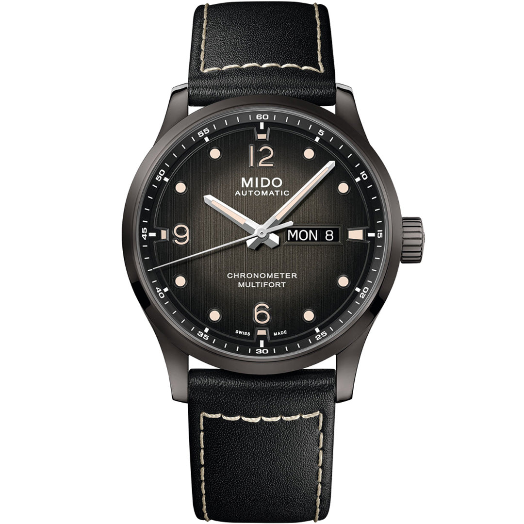 The MIDO Multifort M Chronometer Automatic 42mm features a black dial with white markers, day and date display at 3 o'clock, and a black leather strap with contrasting white stitching. COSC certified.