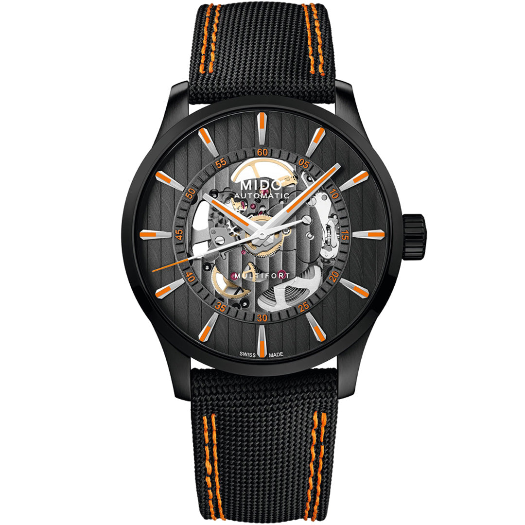 The MIDO Multifort Skeleton Vertigo Automatic 42mm Watch features a black skeleton dial displaying internal gears, orange-accented indices and strap, plus a black textured band with orange stitching.