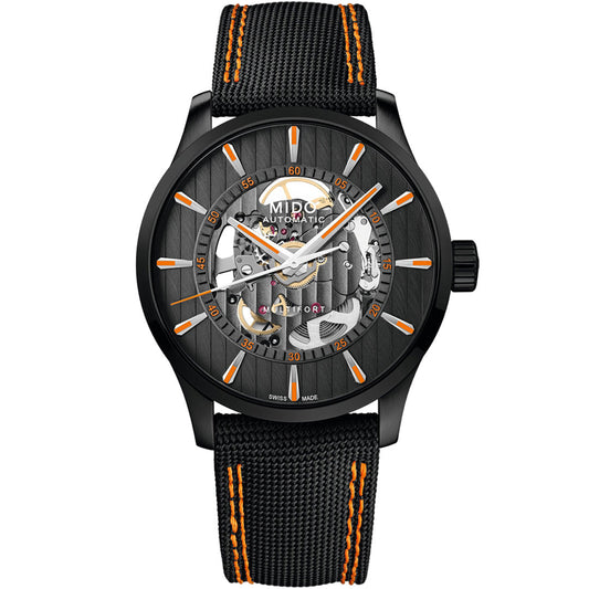 The MIDO Multifort Skeleton Vertigo Automatic 42mm Watch features a black skeleton dial displaying internal gears, orange-accented indices and strap, plus a black textured band with orange stitching.