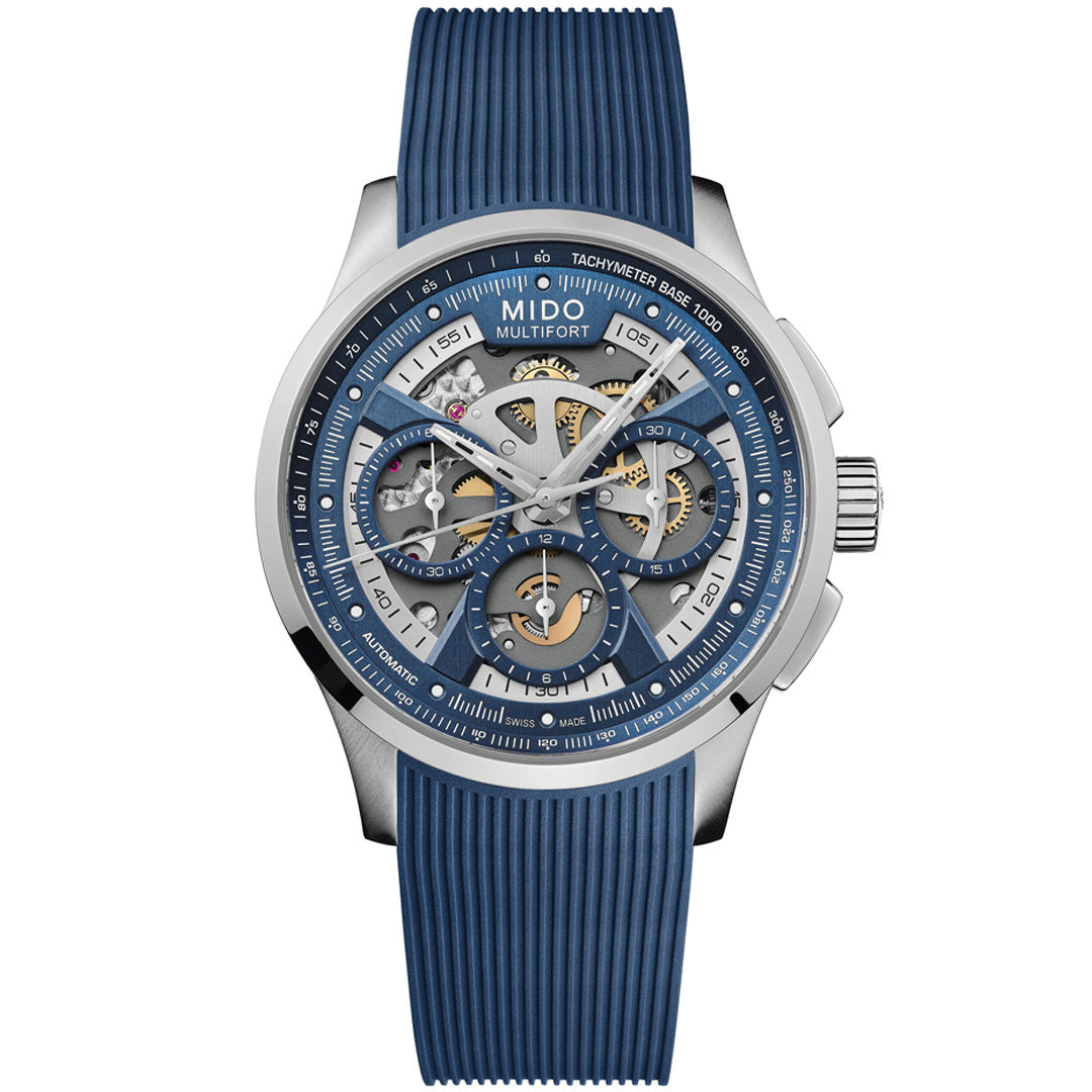 The MIDO Multifort Skeleton Chronograph Automatic 43mm Watch features a silver case, blue skeleton dial with visible gears, chronograph subdials, tachymeter scale, Swiss automatic movement, and a blue textured rubber strap.