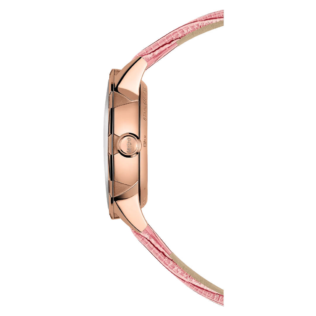 Side view of the MIDO Rainflower Automatic 34mm women’s watch, featuring a rose gold-toned case and pink leather strap with stitching and crown, shown vertically on a white background.