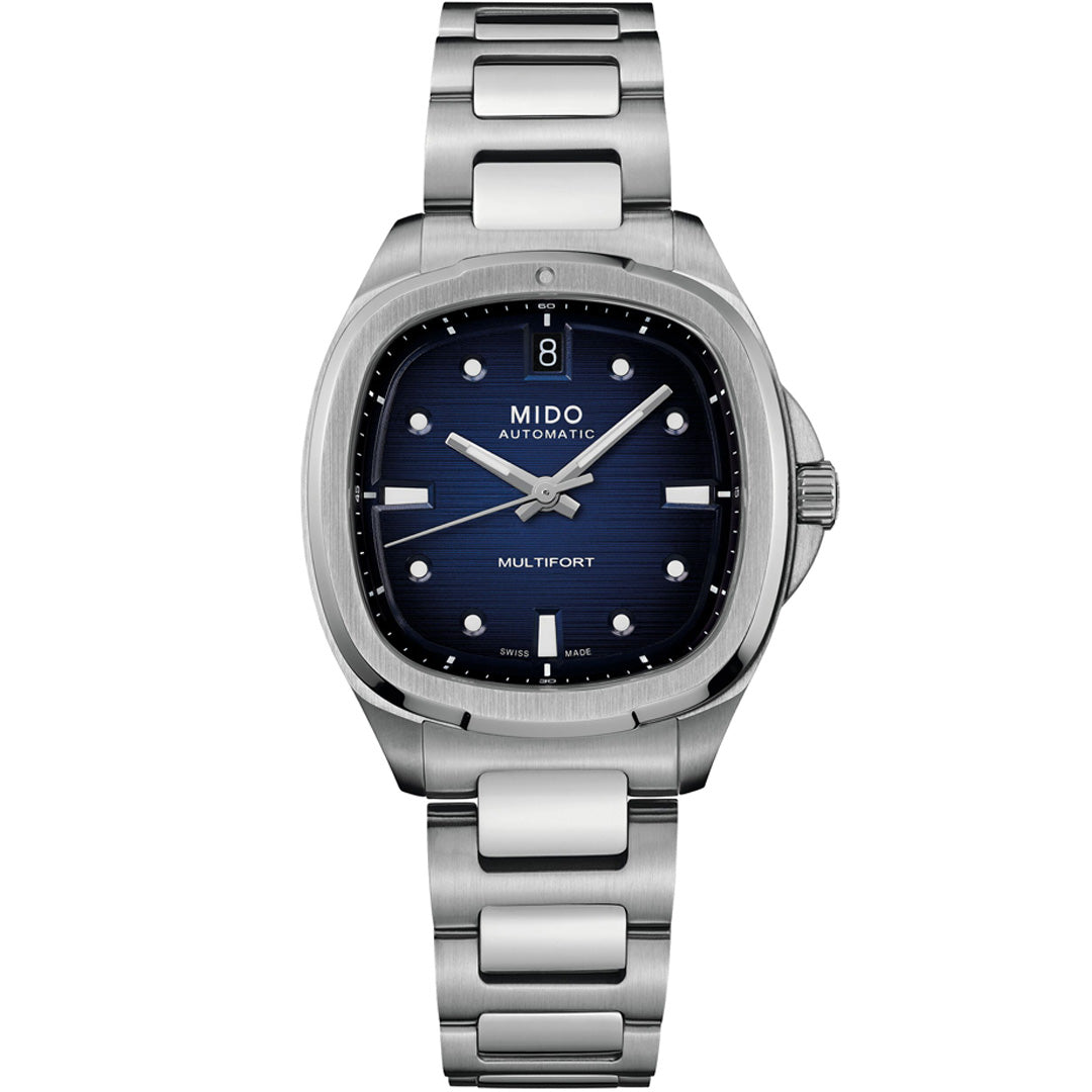 The MIDO Multifort TV 35 Automatic 35mm Watch features a blue dial with silver hour markers, a date display at 12 o’clock, automatic movement, a brushed metal bracelet, and a round-edged square stainless steel case.