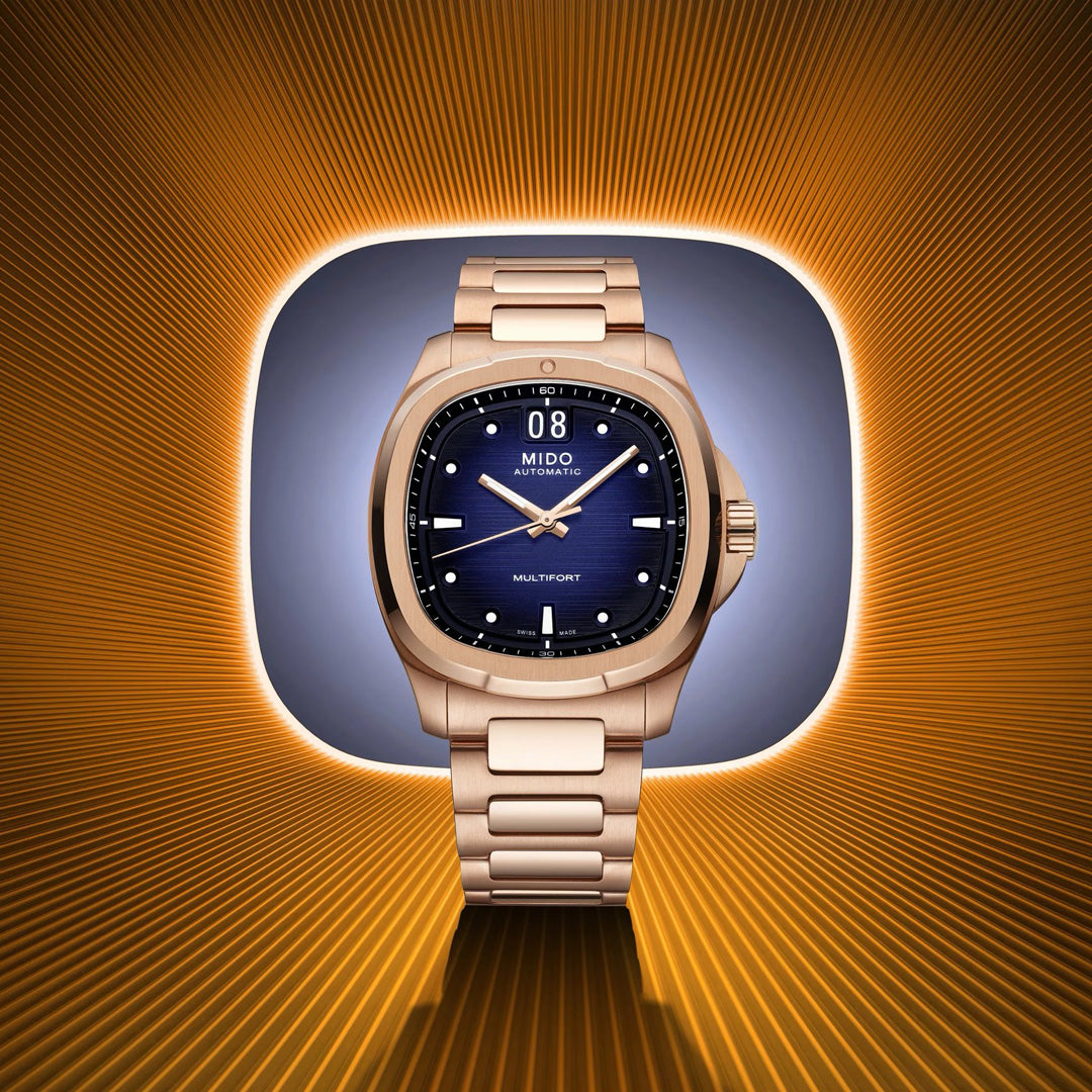 The MIDO Multifort TV Big Date Automatic 39.2mm Watch is centered against a glowing orange and yellow radial background, showcasing its modern Swiss design with a blue dial, silver hour markers, and automatic movement.