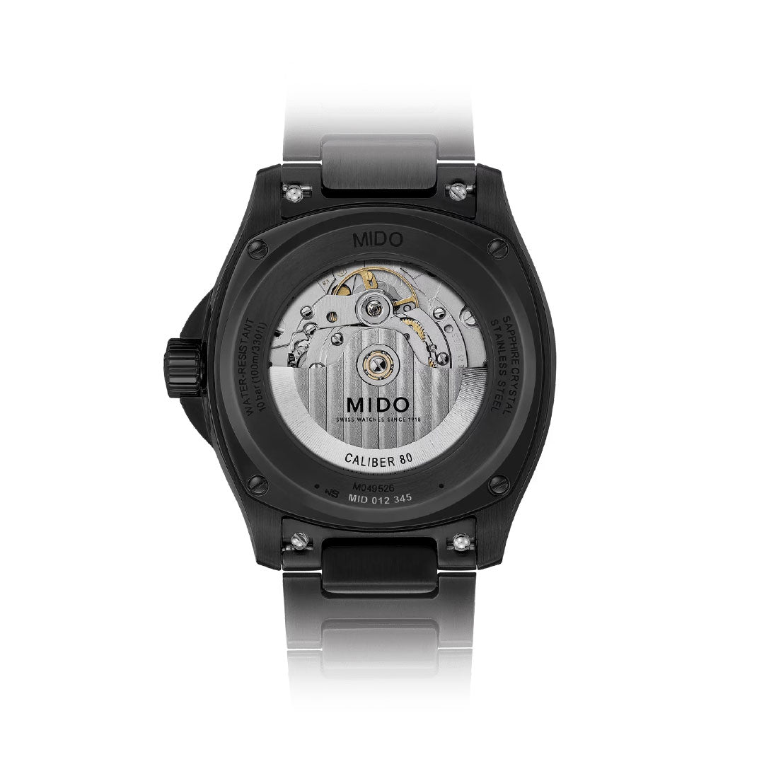 The image shows the back of the MIDO Multifort TV Big Date Automatic 40mm Watch, with a transparent case revealing its Caliber 80 movement, internal mechanisms, stainless steel bracelet, and engraved case back details.