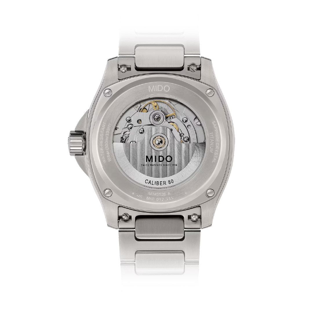 The image shows the back of the MIDO Multifort TV Big Date Automatic 40mm Watch, featuring a transparent case that reveals the "MIDO CALIBER 80" automatic movement, with a stainless steel case and bracelet.