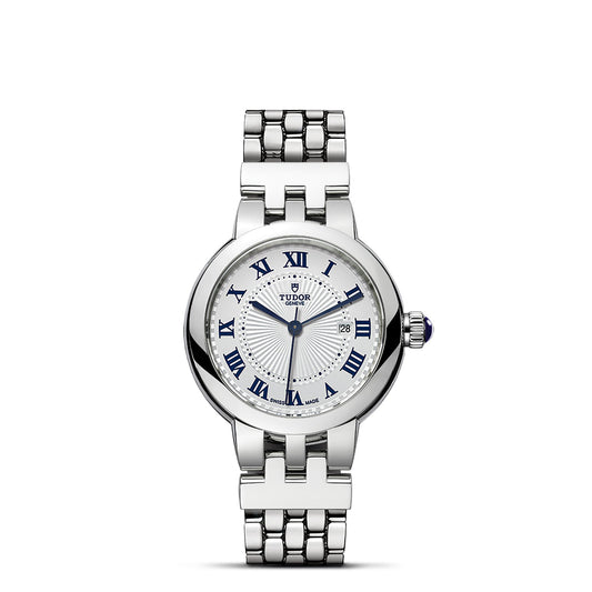 The TUDOR Clair de Rose is a silver wristwatch featuring a steel bracelet. Its white opaline dial showcases blue Roman numerals and includes a date display at 3 o'clock. This sophisticated timepiece is finished with an elegantly refined crown on the side.