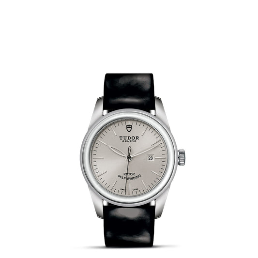 The New Old Stock TUDOR Glamour Date wristwatch from TUDO1 exudes subtle glamour with its minimalist design. With a black leather strap, this elegant timepiece features a round face displaying hour, minute, and second hands along with a small date window on the right side of the dial.