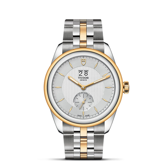 This exquisite wristwatch, the New Old Stock TUDOR Glamour Double Date by TUDO1, features a striking silver and gold bracelet. Its round face is adorned with a date display at the 12 o'clock position, a subdial at 6 o'clock, and is encircled by a gold bezel. Exuding retro-chic style, the prestigious TUDOR name graces the dial.