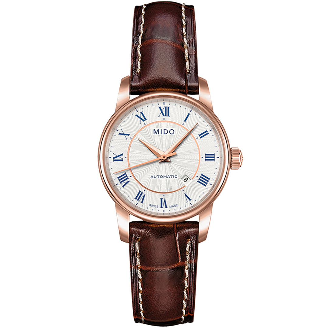 The MIDO Baroncelli II Lady Automatic 29mm Watch features a brown leather strap, rose gold case, white dial with blue Roman numerals, three hands, and “MIDO” branding at the top, highlighting its automatic movement above 6 o’clock.