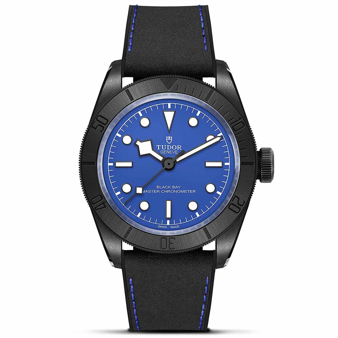 The TUDOR Black Bay Ceramic is a stylish timepiece featuring a bold blue dial complemented by a black rotating bezel with luminous markers, all housed in a sleek ceramic case. It is paired with a black strap enhanced by blue stitching and prominently displays the "TUDOR" branding. The watch showcases time through its elegant hour, minute, and second hands.
