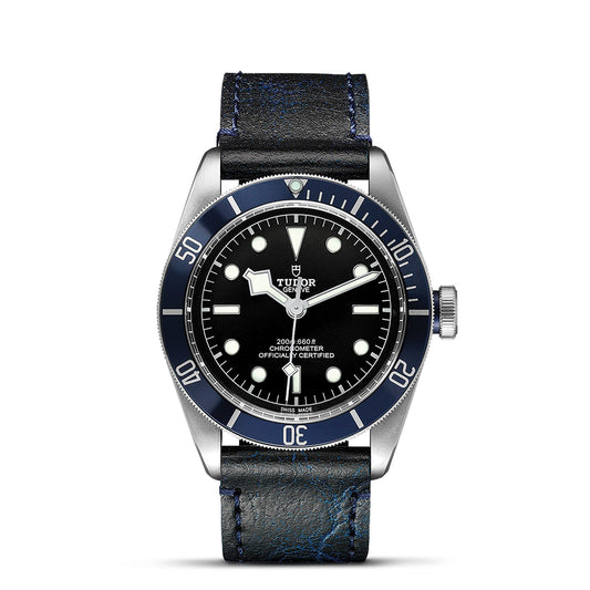 The TUDOR Black Bay wristwatch is a luxurious timepiece influenced by TUDOR's diving watches, showcasing a black dial accented with elegant snowflake hands. Its blue bezel seamlessly pairs with the silver case and luminous hour markers. Finished with a black leather strap and blue stitching, this model embodies elegance and precision.