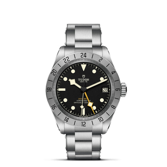 The TUDOR Black Bay Pro, a silver wristwatch from the TUDOR brand, is equipped with a stainless steel band and features a black face with luminescent hour markers and a date display. It distinguishes itself with an hour hand that has a yellow tip, and its technical design includes a 24-hour bezel for tracking dual time zones. This watch is powered by the TUDOR Manufacture Calibre MT5652 movement.