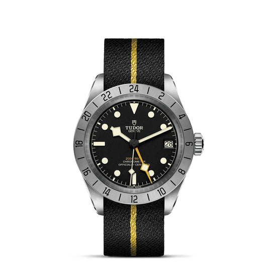 The TUDOR Black Bay Pro wristwatch features a stylish black design with a silver bezel and a strap accented by yellow stripes. Powered by the TUDOR Manufacture Calibre MT5652, it offers dual time zone functionality, prominent luminous markers, and a date display at 3 o'clock. The bezel includes a 24-hour scale.