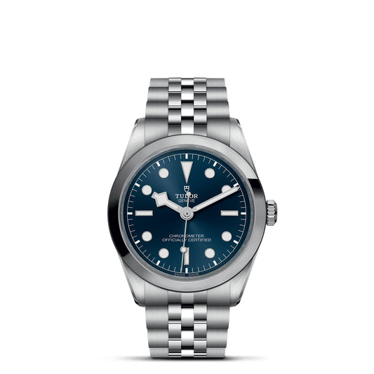 The TUDOR Black Bay One 36 is a stainless steel wristwatch with a five-link bracelet, featuring a blue dial with silver hour markers and a date window. Its three central hands for hours, minutes, and seconds embody the elegance and functionality of TUDOR divers' watches.