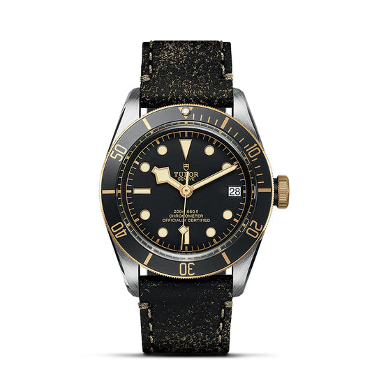 Introducing the TUDOR Black Bay S&G, a luxurious wristwatch showcasing a sophisticated black and gold design. It features a round face adorned with hour markers and minute numerals elegantly placed on the bezel, along with a convenient date display. Complemented by a textured black leather strap, this model is branded with "TUDOR" on the dial, enhancing its elegant appeal.