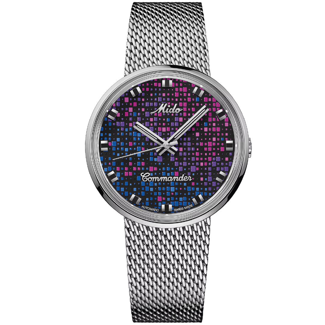 The MIDO Commander Pixel Automatic 37mm watch features a silver mesh band, a blue, pink, and black grid-patterned dial with silver hands and indices, and displays "Mido" and "Commander"; Swiss-made with automatic movement.