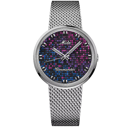The MIDO Commander Pixel Automatic 37mm watch features a silver mesh band, a blue, pink, and black grid-patterned dial with silver hands and indices, and displays "Mido" and "Commander"; Swiss-made with automatic movement.