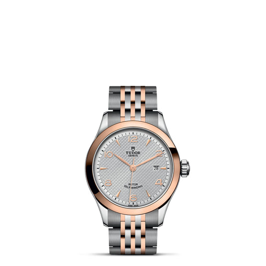 The TUDOR 1926 wristwatch showcases a classic and elegant allure with its silver and rose gold finish. It is adorned with a refined silver dial featuring textured details, luminescent hands, a date display at 3 o'clock, and a sophisticated two-tone bracelet, epitomizing the charm of mechanical timepieces.