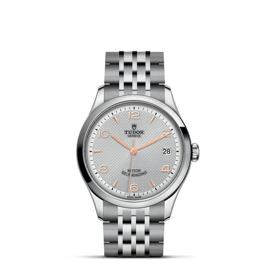 The TUDOR 1926 wristwatch from the brand TUDOR features a silver and stainless steel bracelet. It has a light gray watch face highlighted with gold-tone hour markers and hands, includes a date window at the 3 o'clock position, and displays TUDOR's iconic logo at 12 o'clock.
