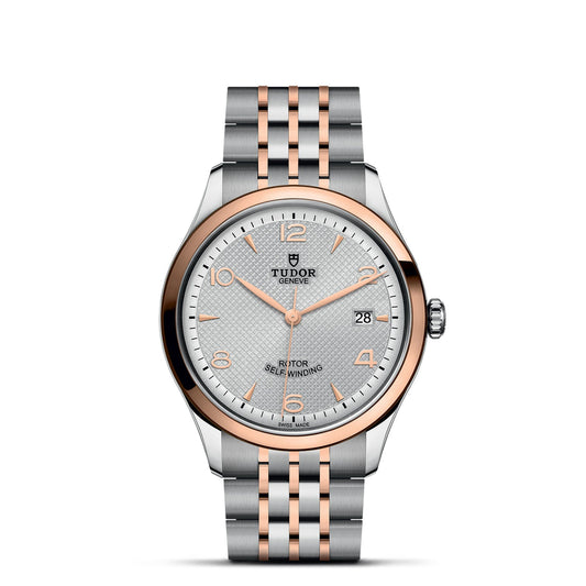 The TUDOR 1926 wristwatch showcases a metal bracelet crafted from silver and rose gold, highlighted by an eye-catching rose gold bezel. Its silver dial, accented with rose gold details, features a date display at the 3 o'clock position. The TUDOR logo is prominently placed at the 12 o'clock mark, highlighting its exceptional mechanical watchmaking craftsmanship.