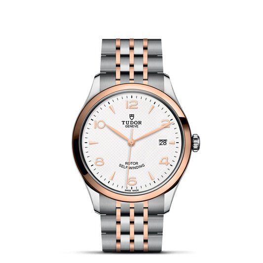 The TUDOR 1926, a luxury wristwatch from TUDOR, features an elegant two-tone gold and silver metal band. Its round white dial is adorned with gold hour markers and hands and prominently displays "Tudor Genève." This exquisite mechanical timepiece also includes a date function positioned at 3 o'clock.