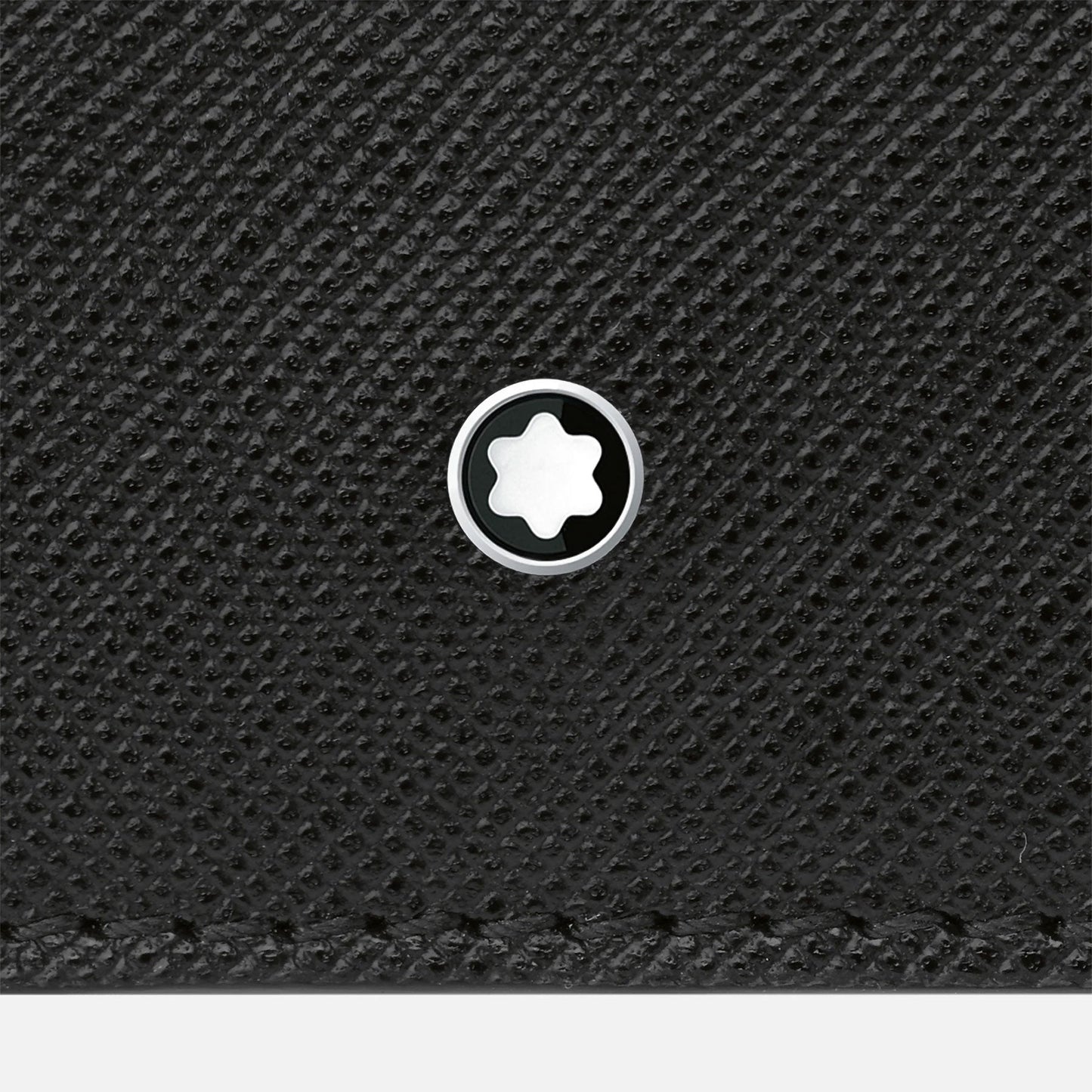 A close-up of the Montblanc Sartorial Wallet 6cc highlights a small, circular metal emblem adorned with the Montblanc logo, featuring a white star-like symbol at its center.