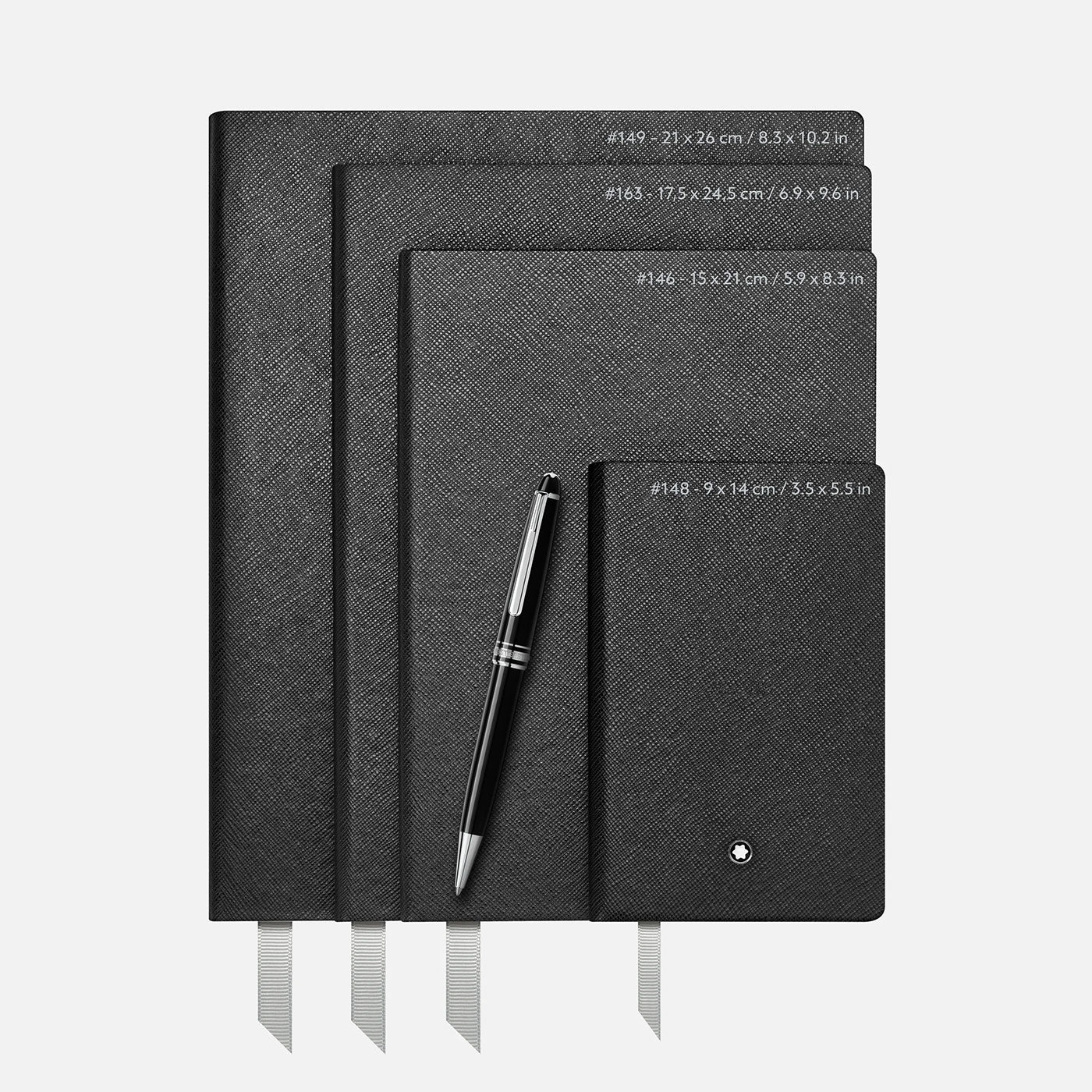 Four Montblanc Fine Stationery Black Lined #146 Notebooks, known for their elegant fine stationery appeal, are stacked with a silver and black pen resting on them. These notebooks include ribbon bookmarks and size labels on the cover, highlighted by a sleek Montblanc emblem that adds sophistication against the plain white background.