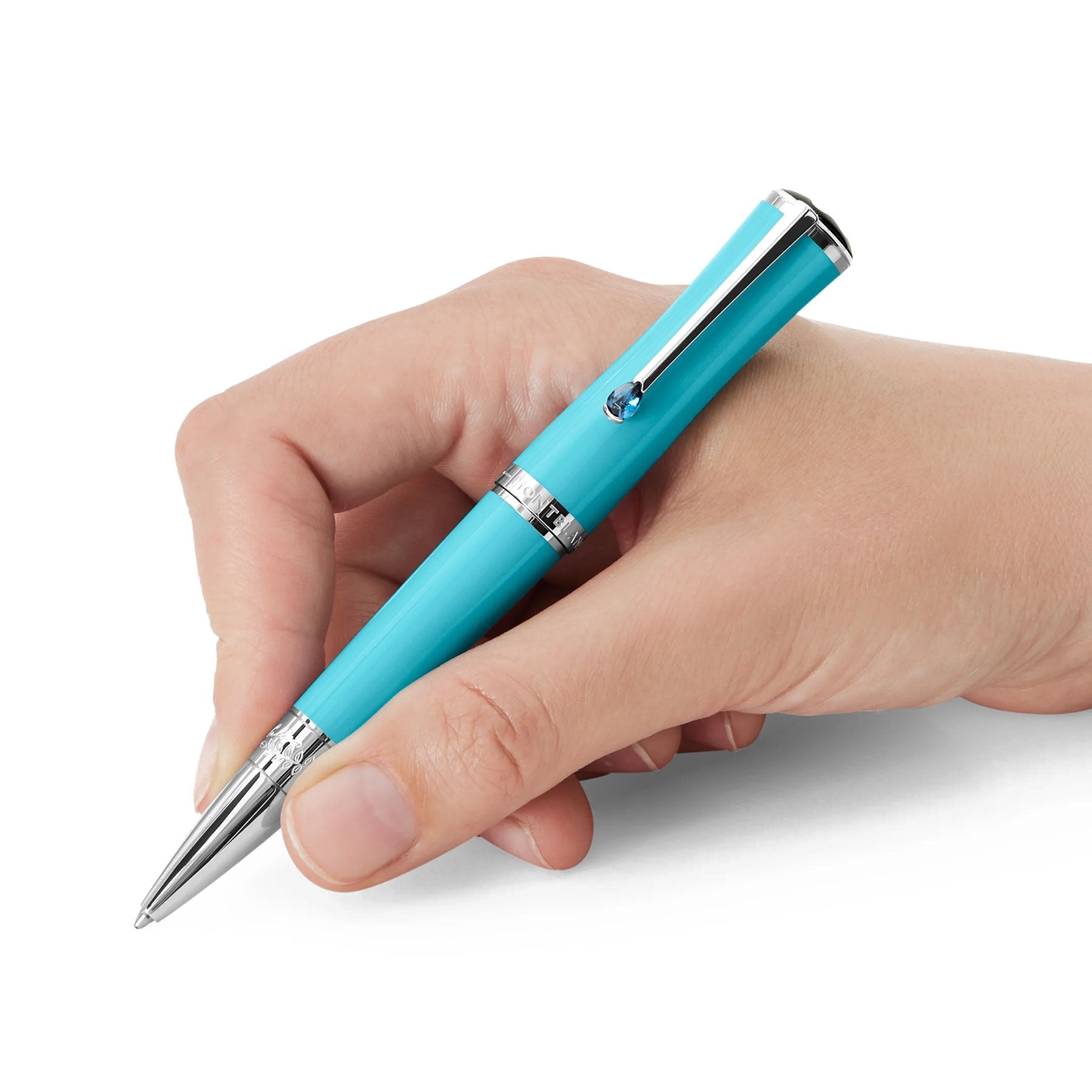 A hand gracefully holds a Montblanc Muses Maria Callas Special Edition Blue Resin Platinum Plated Ballpoint Pen, evocative of the Aegean Sea, adorned with platinum accents. The pen is poised between the thumb and fingers, ready for writing against a plain white background.