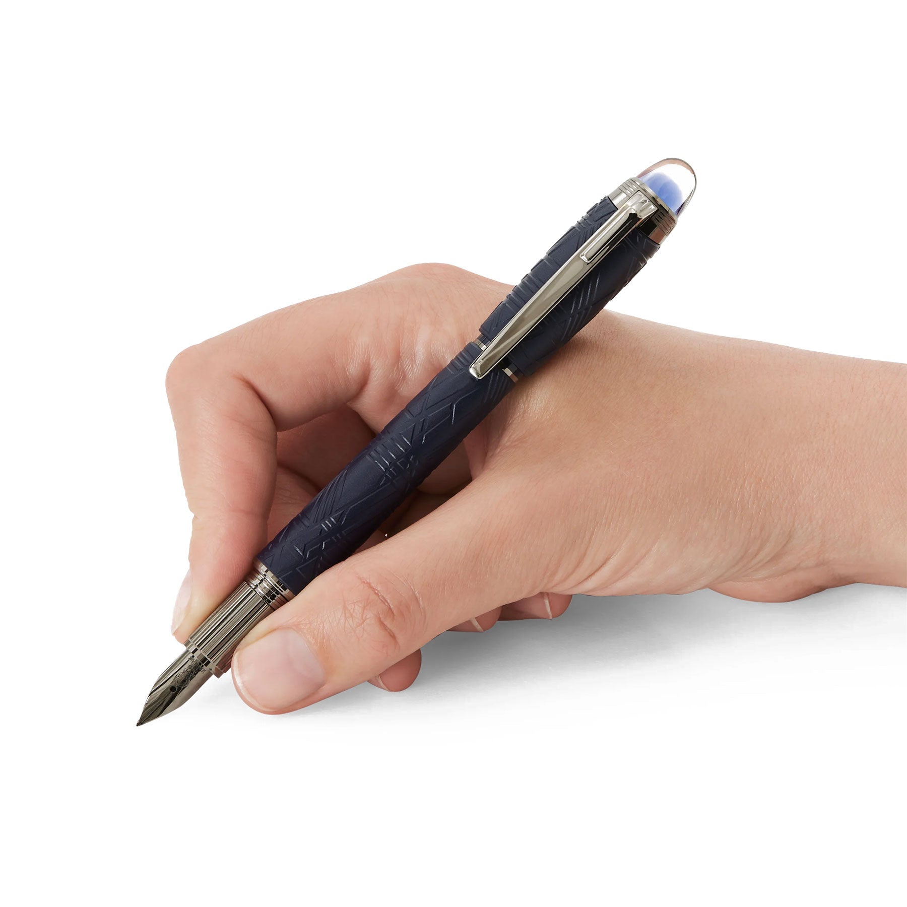 A hand is holding a luxurious Montblanc Starwalker Blue Resin Platinum Plated Fountain Pen, its barrel reminiscent of the Widmanstätten Pattern with deep blue textures and silver accents, poised to write against a pristine white background.