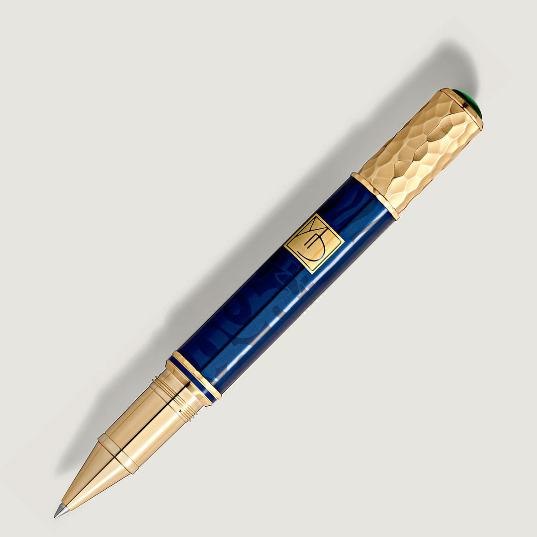 The Montblanc Masters of Art Homage To Gustav Klimt Limited Edition 4810 Rollerball Pen features a golden textured cap and accents, deep blue barrel, and visible metal tip, shown on a light background.