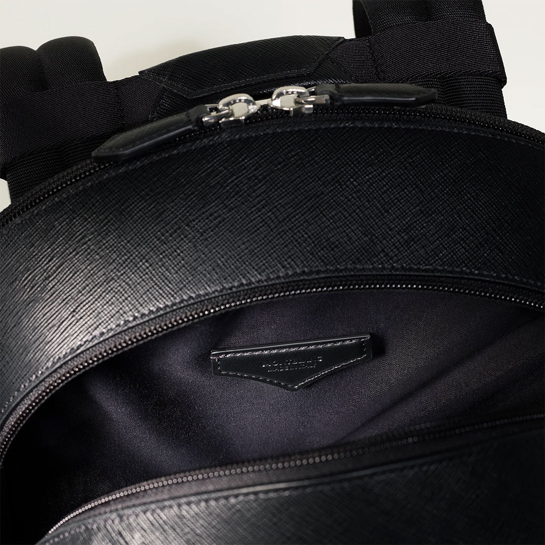 Close-up of the Montblanc Sartorial Medium 3 Compartments Leather Backpack Bag, featuring black Saffiano leather, a partially opened zipper showing the smooth black interior, and an inner stitched leather label.