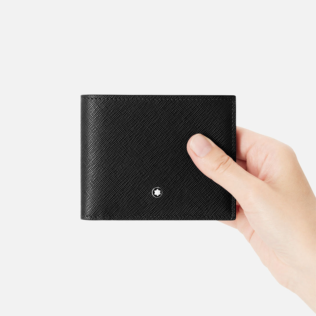 A hand holds the Montblanc Sartorial 6cc Leather Wallet, crafted from textured Saffiano leather with a silver Montblanc logo and credit card slots, shown against a plain white background.