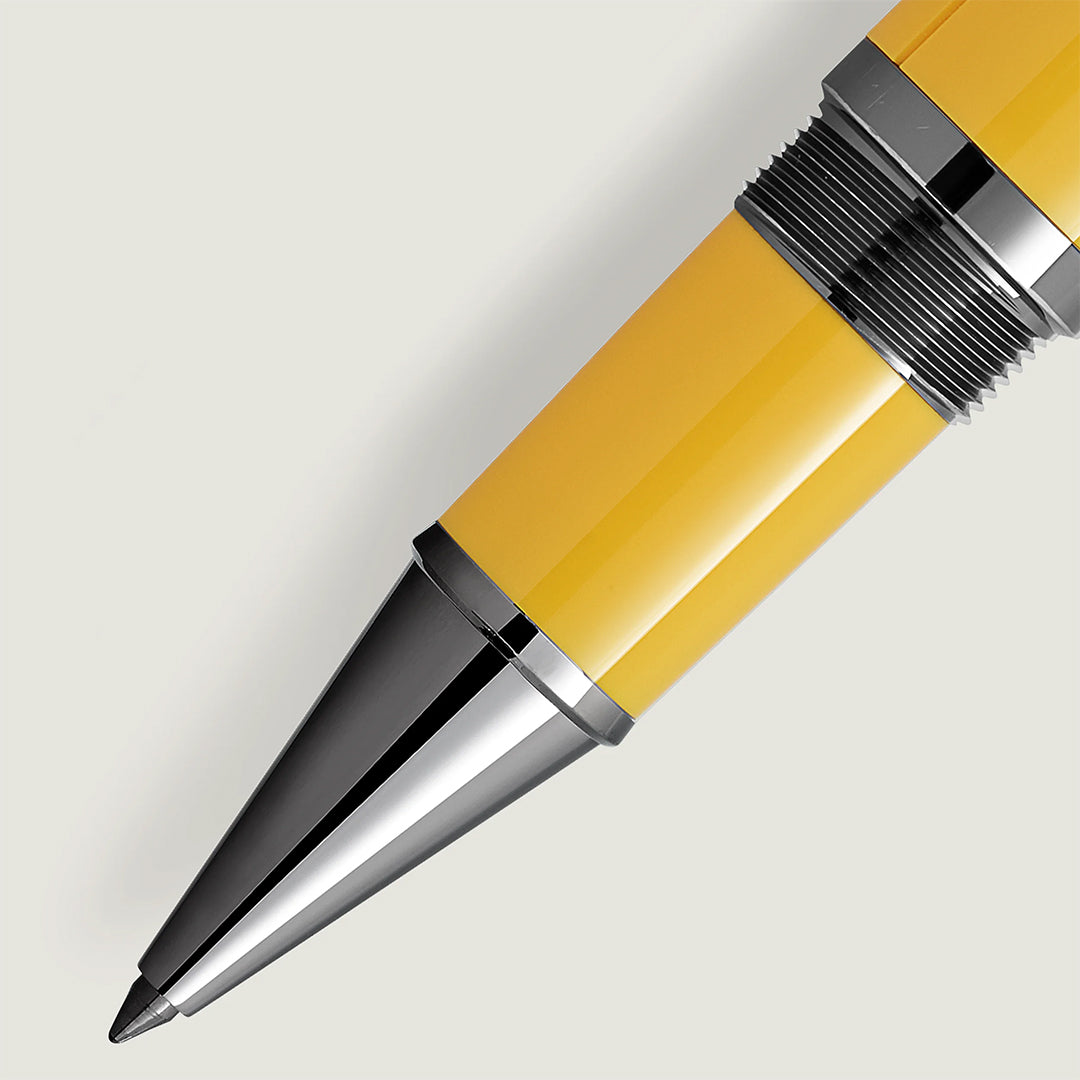 Close-up of the Montblanc Great Characters Enzo Ferrari Special Edition Giallo Modena Rollerball Pen on a light gray background. It showcases a shiny metallic tip and textured grip, embodying modern minimalism and comfort, with a sleek yellow and silver design.