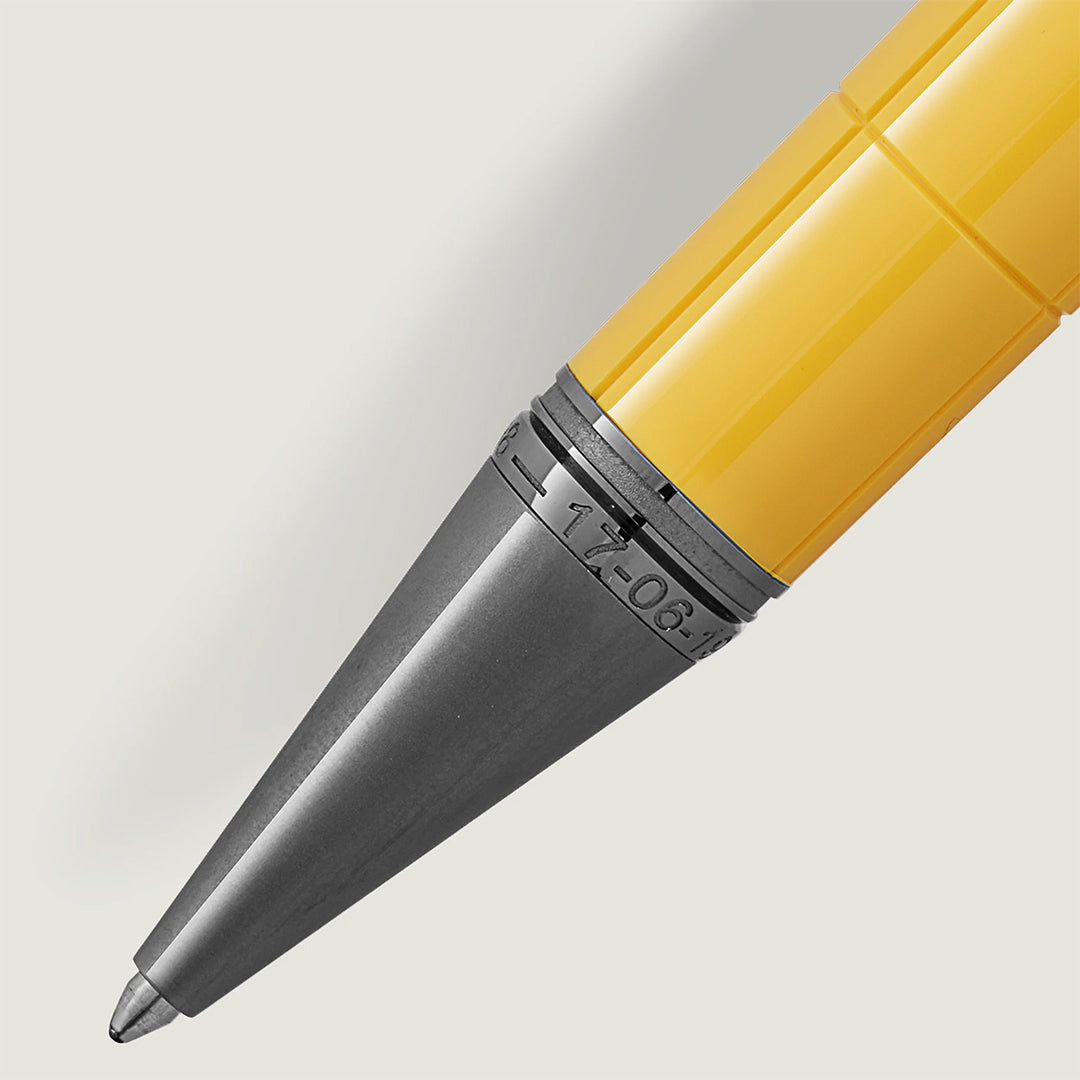 A close-up of the Montblanc Great Characters Enzo Ferrari Special Edition Giallo Modena Ballpoint Pen showcases its shiny yellow body and silver metallic conical tip against a light gray background, embodying elegance reminiscent of Ferrari's racing legacy.