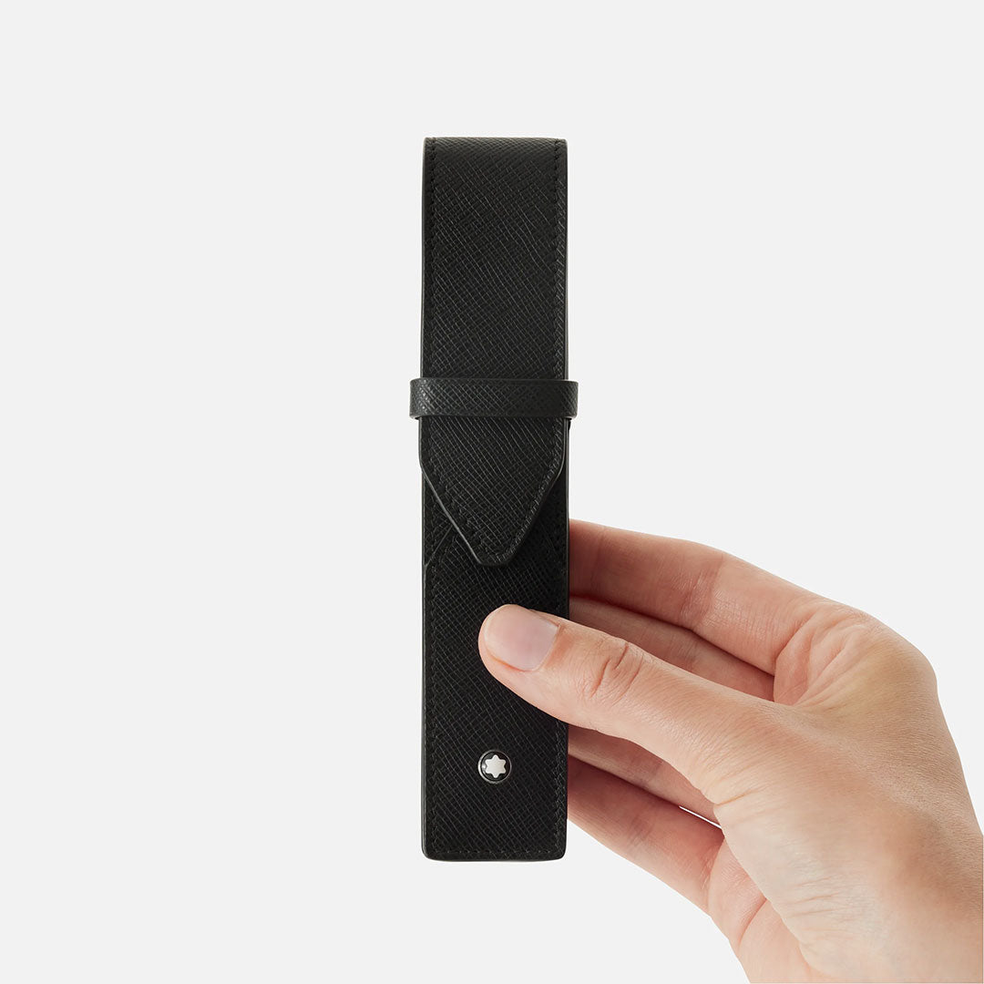 A hand holds the Montblanc Sartorial 1-Pen Leather Pouch by Montblanc, a sleek black full-grain leather case with a flap closure and small circular emblem, shown against a plain white background.