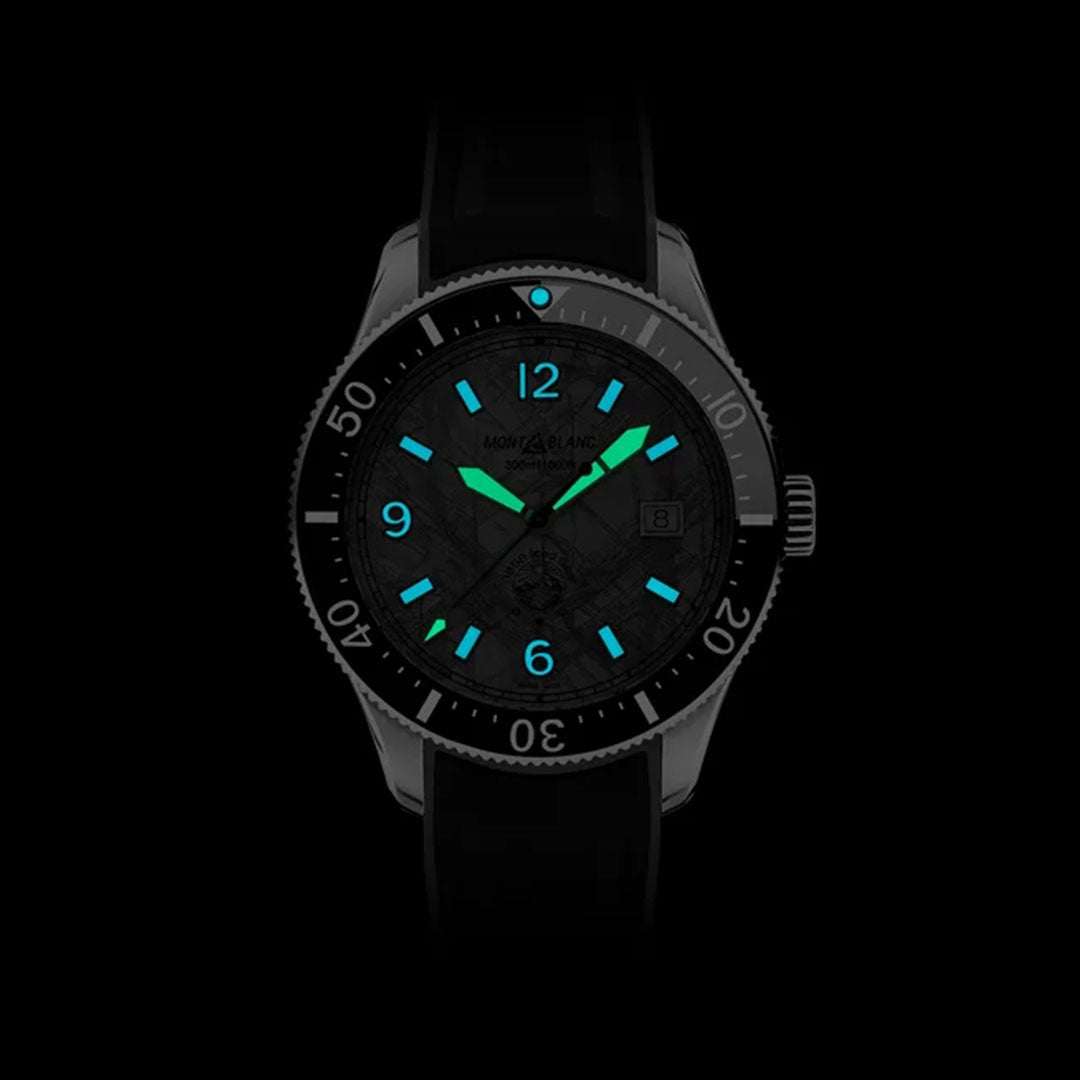 The Montblanc 1858 Iced Sea Automatic Date 41mm Watch, featuring a dark dial with luminous blue and green hands and hour markers, stands out impressively. Its bezel, accentuated with white numerals against a black background, further enhances its elegance, making it an ideal choice for scuba diving enthusiasts.