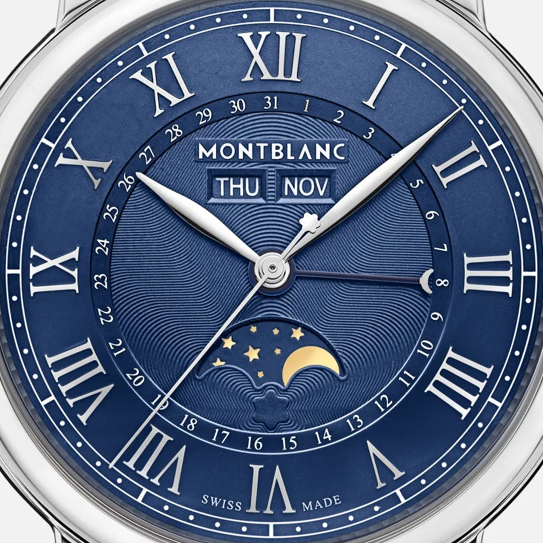 Close-up of the Montblanc Star Legacy Full Calendar Automatic 42mm Watch face, showcasing Roman numerals against a blue background. The date is displayed as "Thu Nov," accompanied by a full calendar. At the bottom, there is an adornment featuring a night sky with stars and a crescent moon. The watch also includes an interchangeable strap system, with "Swiss Made" inscribed prominently.