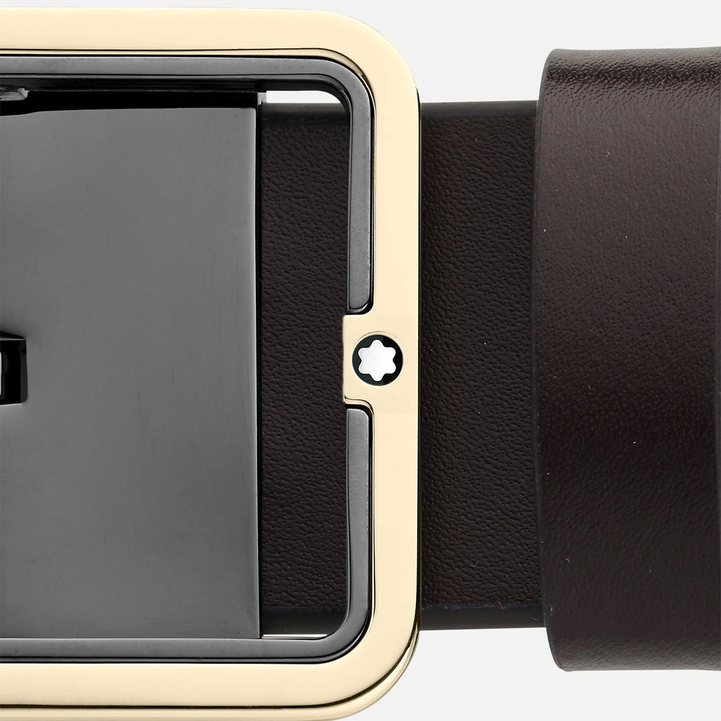 Close-up of the Montblanc Reversible 35mm Black/Brown Leather Belt, showcasing its sleek design and smooth texture. The rectangular gold and black buckle features a subtle star-shaped detail in the center, adding a touch of modern elegance.