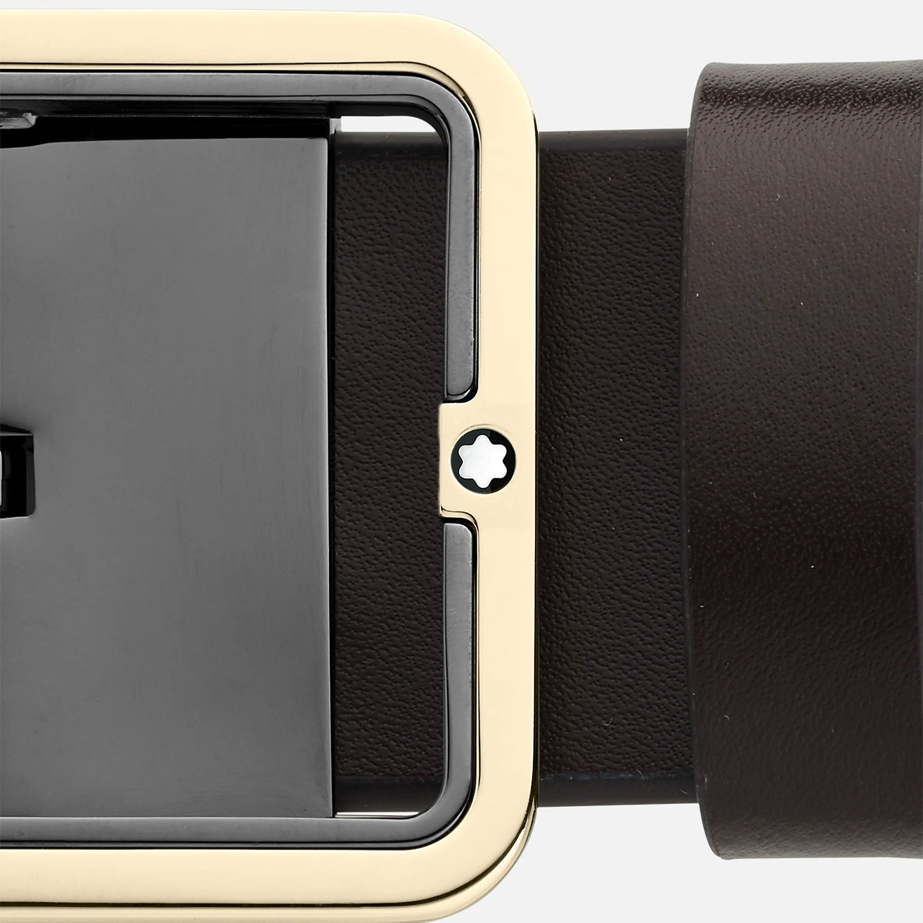 Close-up of the Montblanc Reversible 35mm Black/Brown Leather Belt, showcasing its sleek design and smooth texture. The rectangular gold and black buckle features a subtle star-shaped detail in the center, adding a touch of modern elegance.