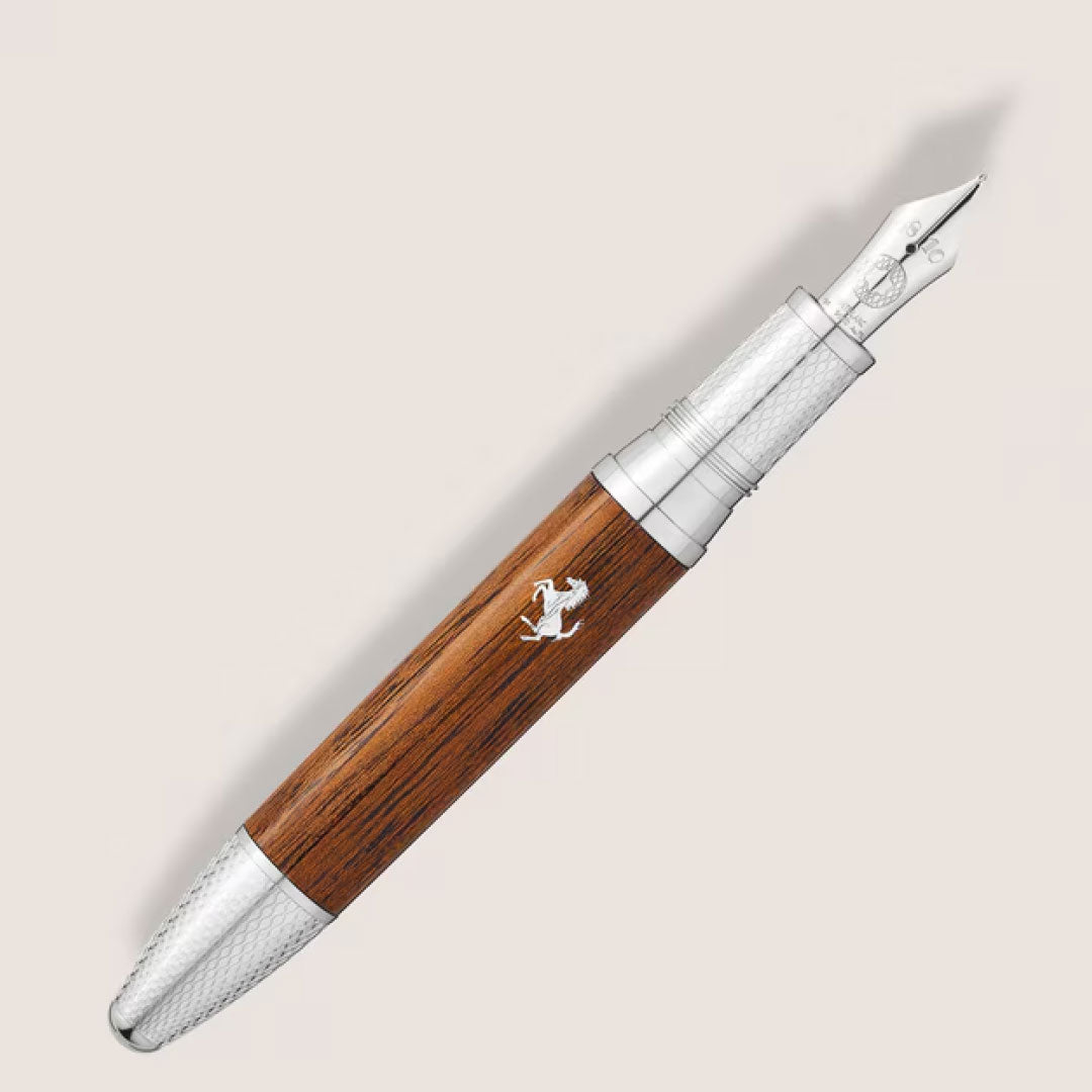The Montblanc Meisterstück Great Masters Ferrari Tailor Made Classica Special Edition Fountain Pen features a wooden barrel, silver accents, and a prancing horse logo, displayed on a light beige background.
