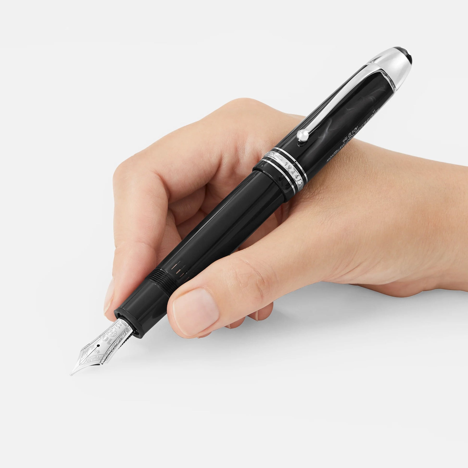 A hand holds the Montblanc Meisterstuck The Original Collection 149 Fountain Pen M, elegant in black with silver accents, poised to write against a plain, light background.