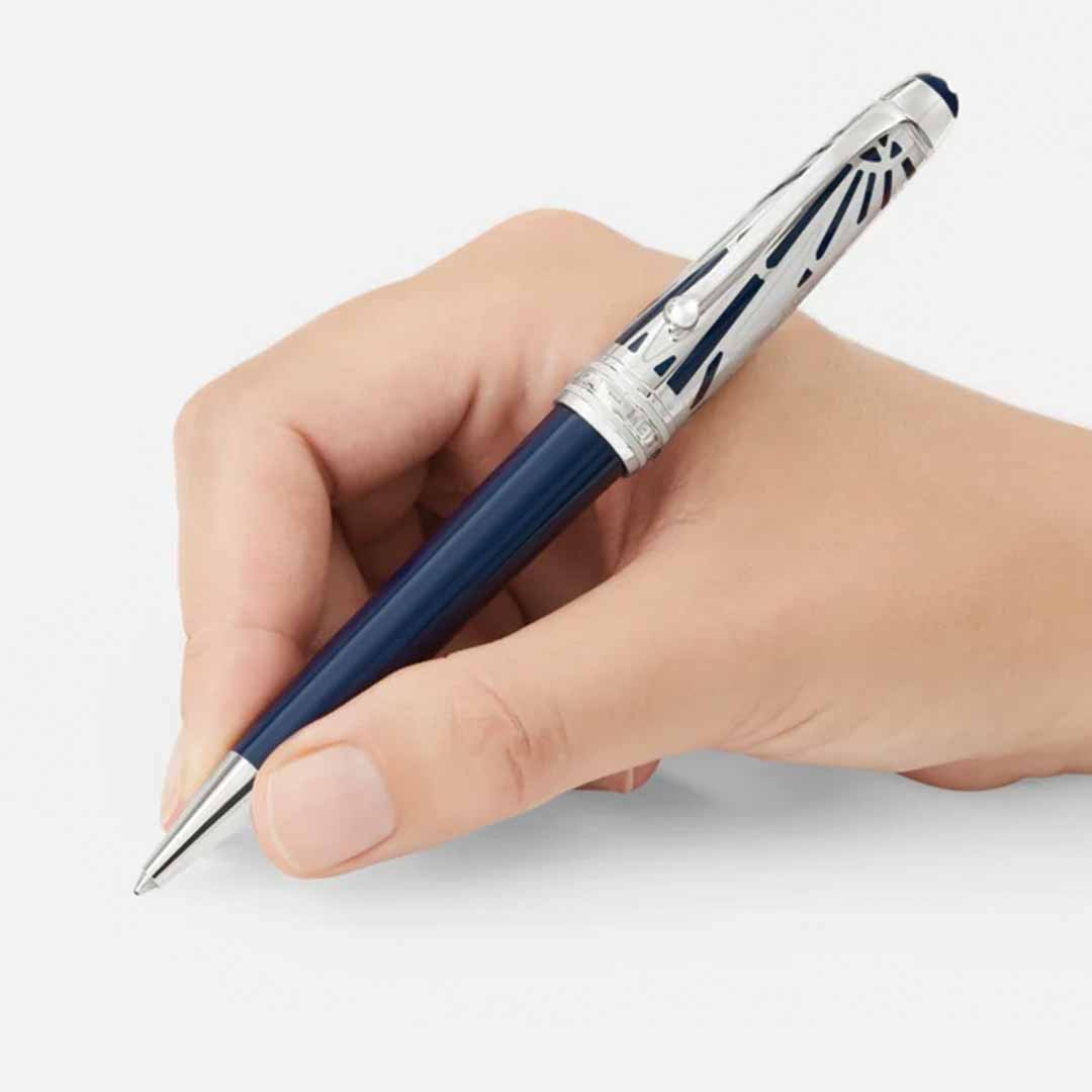 A hand holds a refined blue and silver Montblanc Meisterstuck The Origin Collection Doue Midsize Ballpoint Pen, featuring detailed metal accents on the cap. This exquisite writing piece is poised above a blank surface, ready to write.