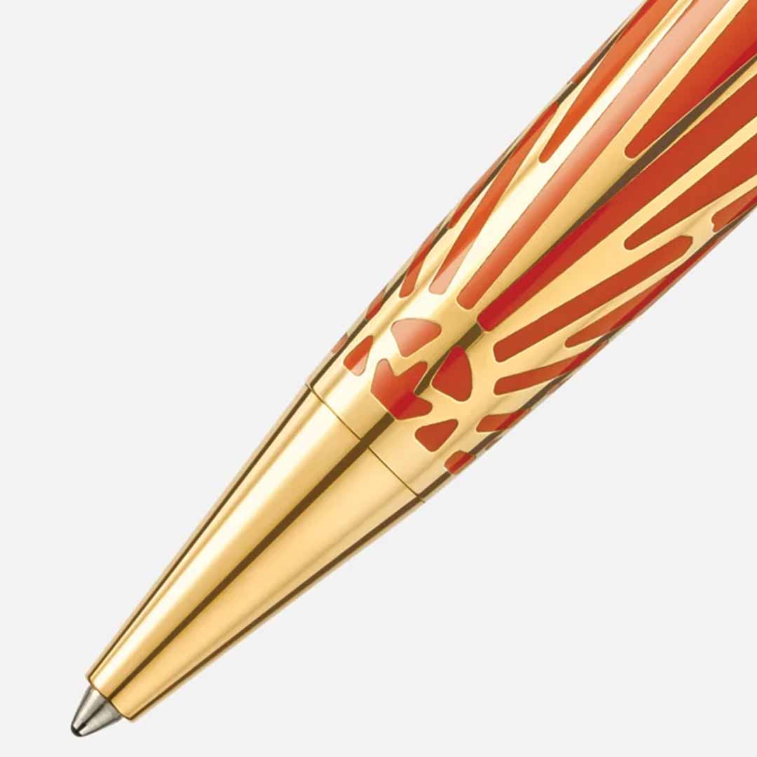 A detailed view of the Montblanc Meisterstuck The Origin Collection Solitaire Midsize Ballpoint Pen reveals its luxurious design, featuring a gleaming gold surface embellished with radiant red sunburst patterns, offering a captivating contrast against the simple white backdrop.