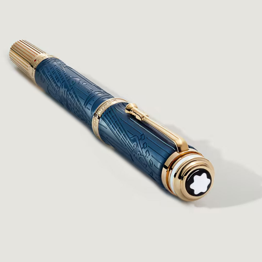 The Montblanc Great Characters Homage to Queen Special Edition Fountain Pen features a luxury blue design with gold accents, intricate barrel patterns, and a white star emblem on the cap, beautifully displayed on a light background.