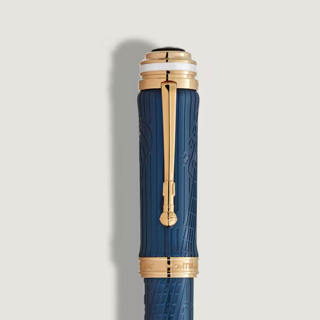 A close-up of the Montblanc Great Characters Homage to Queen Special Edition Fountain Pen showcases its blue barrel, gold accents, and engraved "Montblanc" gold band, set against a simple light background.
