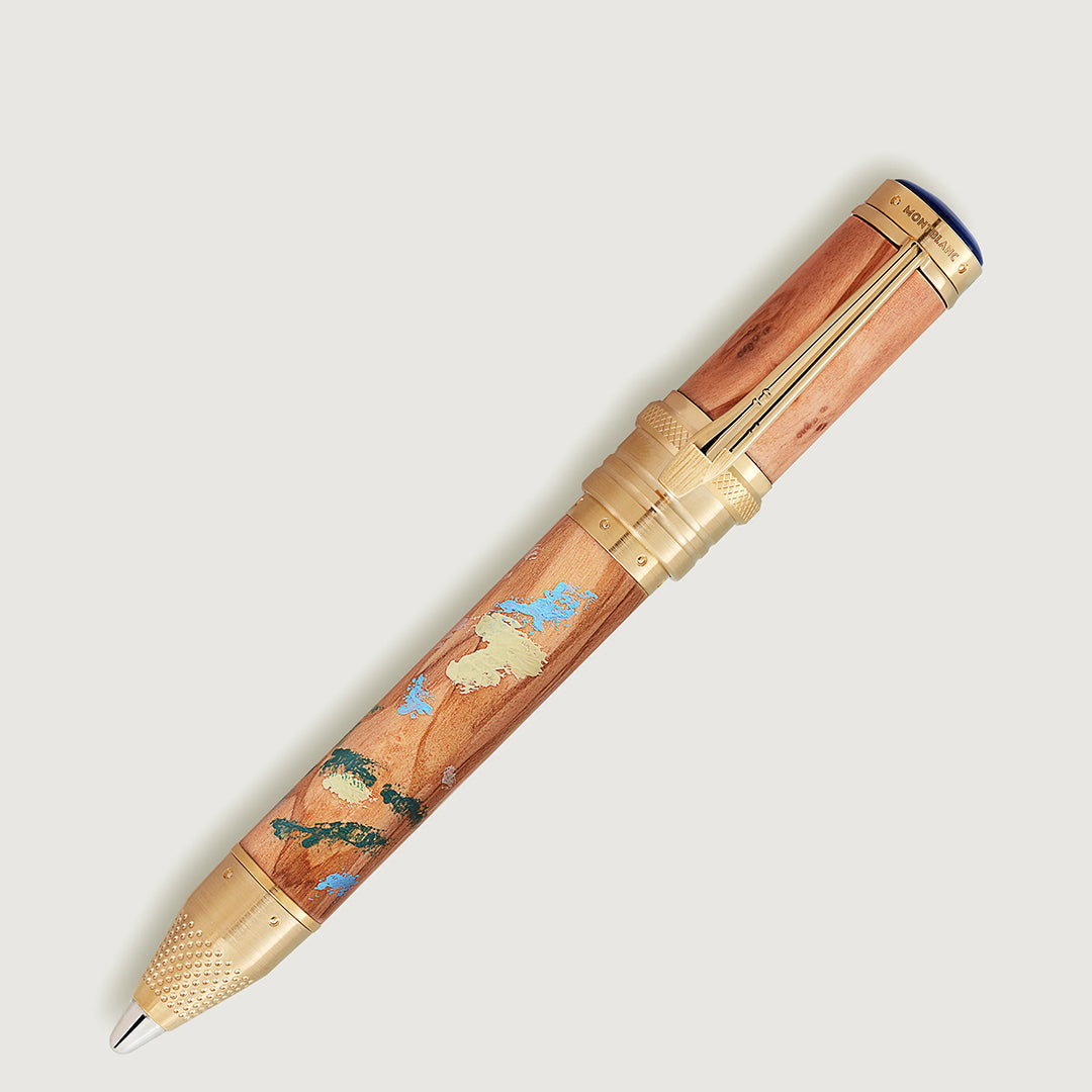 Close-up of an elegant Montblanc rollerball pen from the Masters of Art Homage to Pierre-Auguste Renoir Limited Edition 4810, featuring a wooden finish, gold accents, and Impressionism-inspired inlays in blue and green hues. "Montblanc" is engraved on the cap with a refined gold clip.