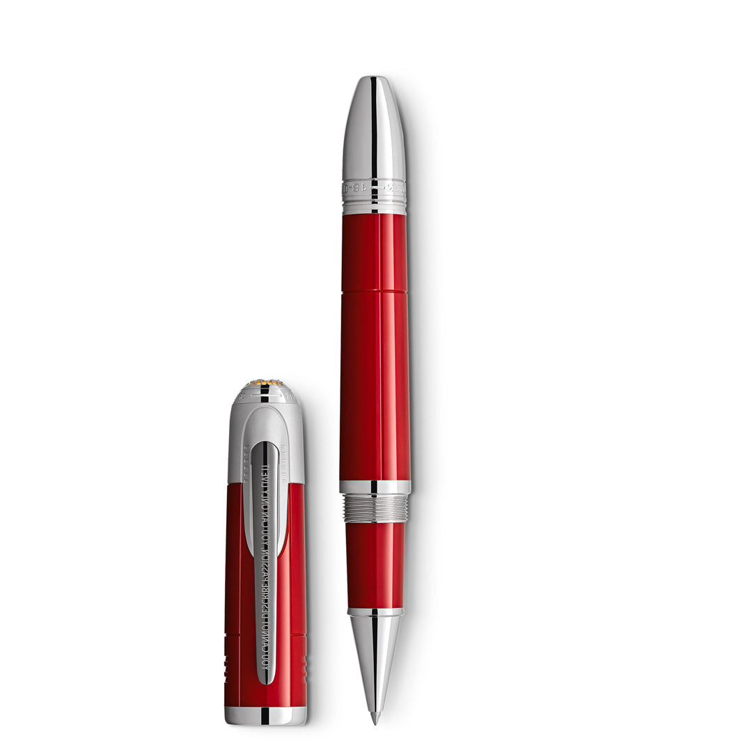 A Montblanc Great Characters Enzo Ferrari Special Edition Rollerball Pen is displayed with its cap removed and placed alongside it on a white background. This luxury writing instrument features striking red and silver hues, shiny metallic accents, and a sleek, elegant design that reflects the exceptional craftsmanship of Montblanc.