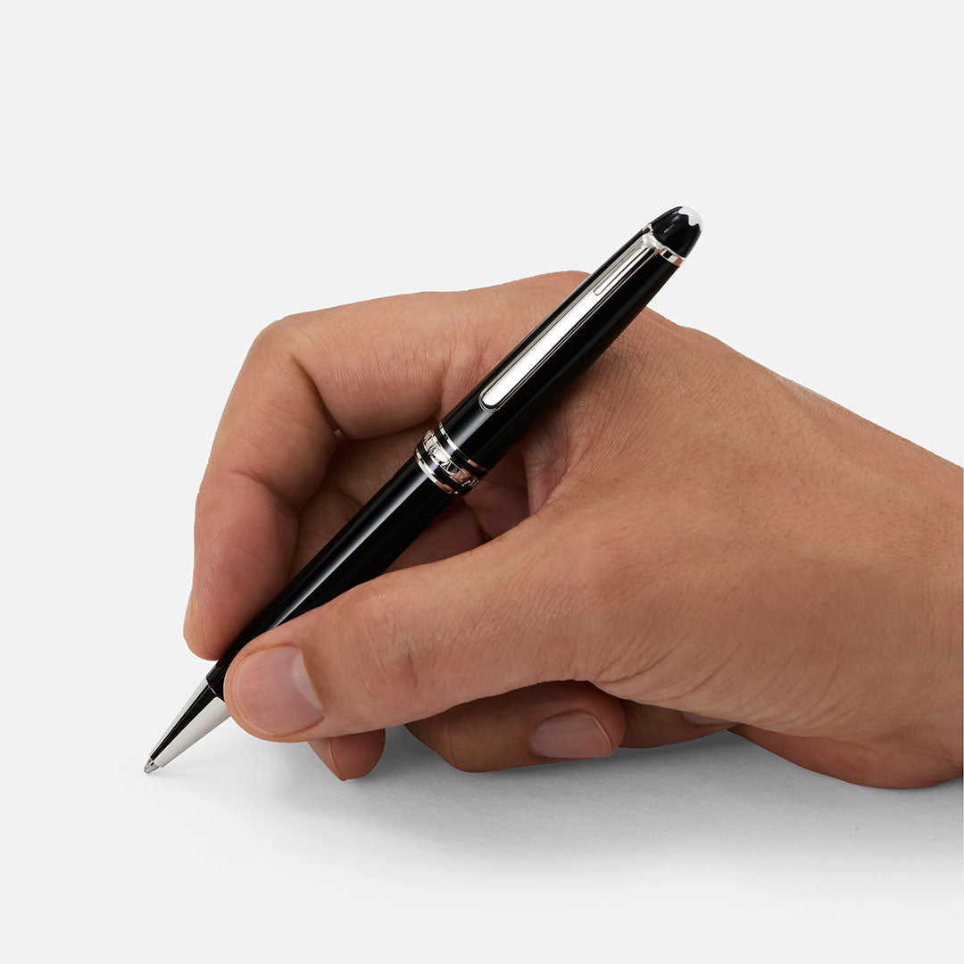 A hand holds a Montblanc Meisterstuck Platinum Coated Ballpoint Pen by Montblanc, featuring a platinum-coated clip, ready to write on a blank white surface.