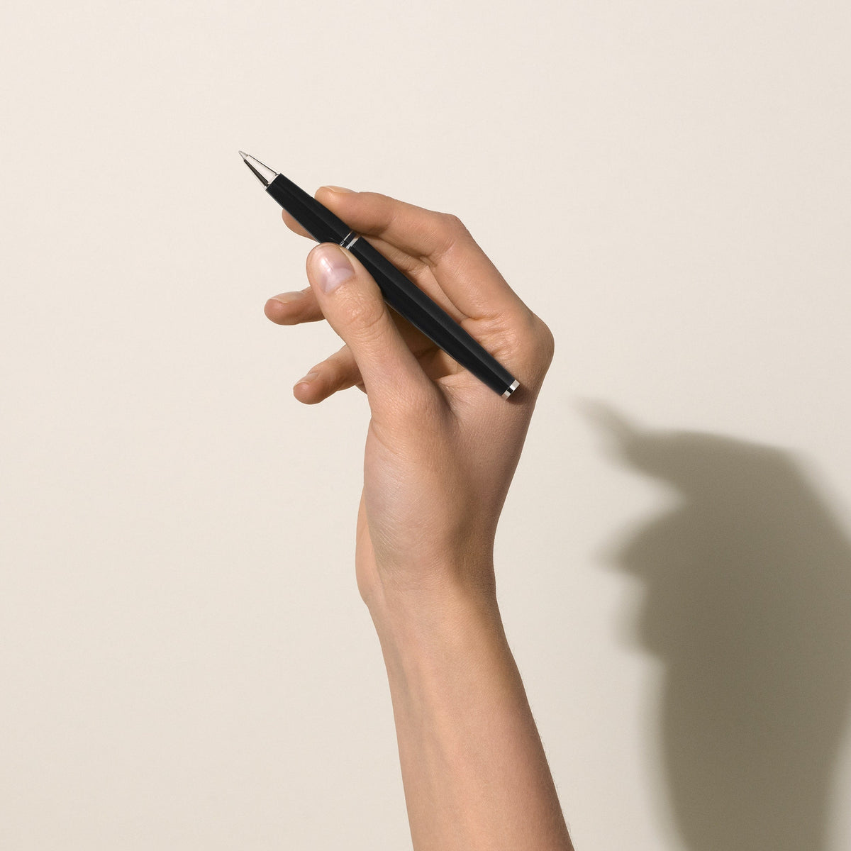 A hand holding a sleek black Montblanc PIX Black Rollerball Pen with a Bauhaus design.